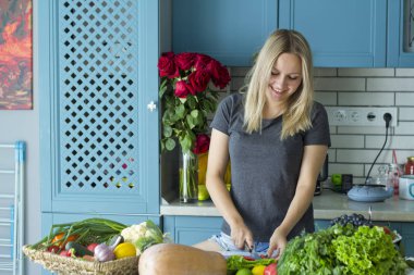 Kız mutfakta sebze ile sağlıklı yiyecek hazırlanıyor. Vejetaryen mutfağı. Onun yirmili genç bir beyaz. Sağlıklı beslenme kavramı.