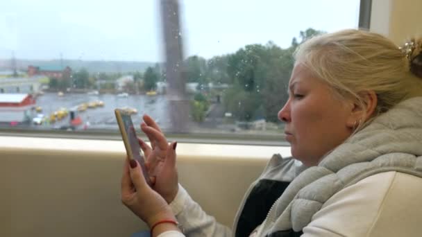 女性は列車に乗る、携帯電話でメッセージを書き込みます. — ストック動画