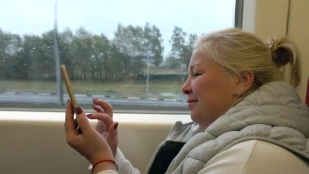 Een vrouw rijdt een trein, schrijft een bericht op een mobiele telefoon. — Stockvideo