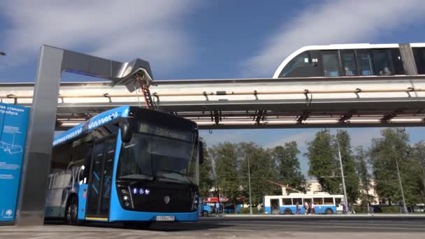 Moscú, Rusia-septiembre de 2017: El concepto de transporte urbano. Autobús eléctrico azul en la estación de carga. Tren moderno que pasa por el monorriel. El concepto de futuro ecológico . — Vídeos de Stock