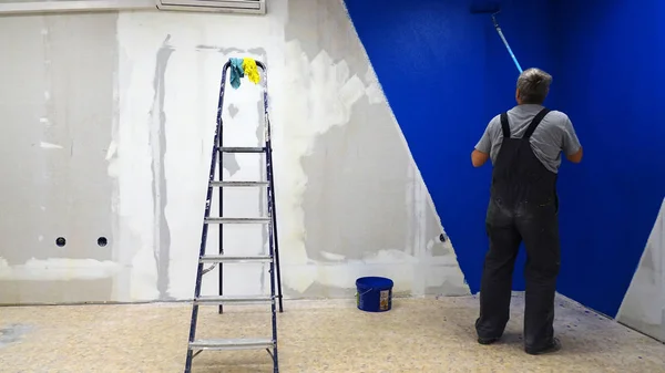 The roller paints the wall blue.worker, vacancy — Stock Photo, Image