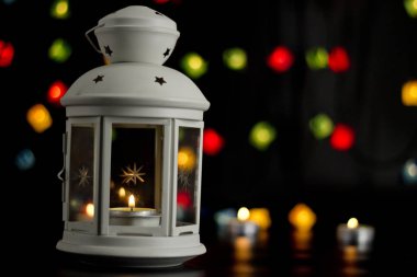Noel beyaz fener renkli ışıklar garland, bokeh arka plan üzerinde yanan bir mum ile.