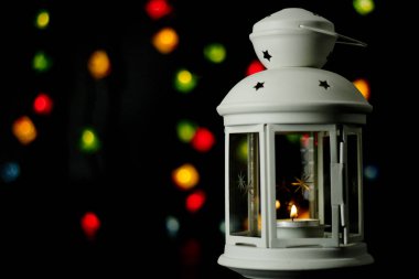 Noel beyaz fener renkli ışıklar garland, bokeh arka plan üzerinde yanan bir mum ile.