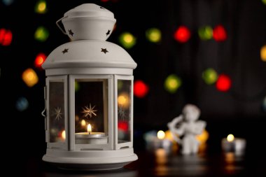 Noel beyaz fener renkli ışıklar garland, bokeh arka plan üzerinde yanan bir mum ile.