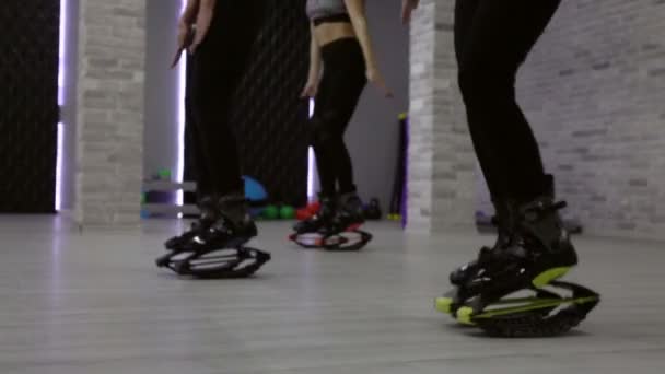 Een vrouwelijke groep van drie jonge, sexy meisjes Kangoo Jumps in de sportschool. — Stockvideo