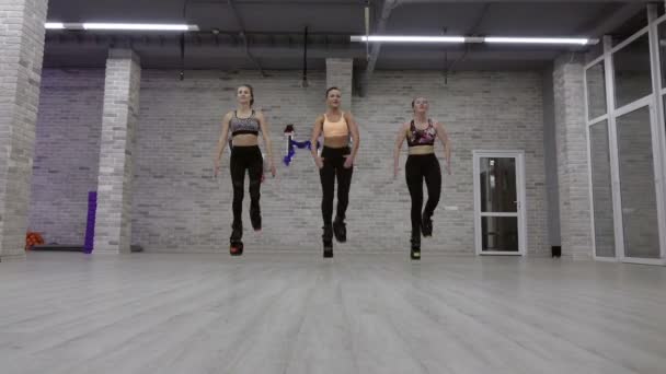 Um grupo feminino de três meninas jovens e sexy Kangoo Salta no ginásio . — Vídeo de Stock
