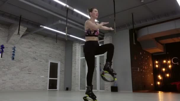 Young, sexy girl Kangoo Jumps in the gym. — Stock Video