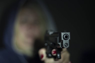 Bir kadın onun elinde bir silah tutan ve kameraya işaret eder. Silahı cephesinde odaklanmak.