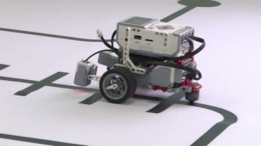 Üç tekerlekli bir robot ile beyaz bir masaya gidiyor. Akıllı robot