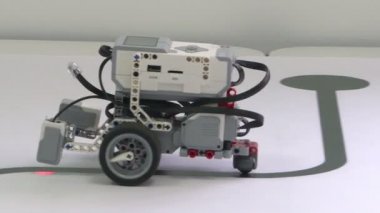 Üç tekerlekli bir robot ile beyaz bir masaya gidiyor. Akıllı robot