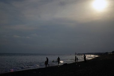 Deniz kıyısında insan siluetleri.