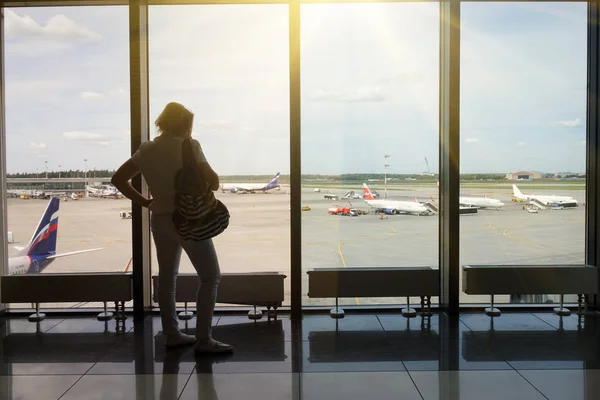 Молодая женщина со смартфоном в руках, силуэт в аэропорту. Самолет на заднем плане. Концепция воздушного транспорта . — стоковое фото
