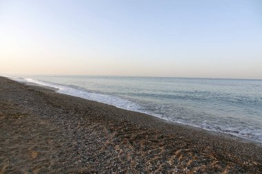 Arka planda çakıl taşı plajı ve mavi gökyüzü