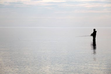 Bir balıkçı batımında silüeti. Gölde balık tutma.