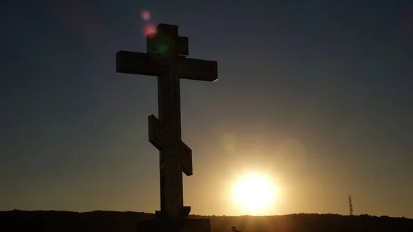 Το σύμβολο της χριστιανικής και της καθολικής εκκλησίας: μια απεικόνισή του ένα σταυρό κατά το ηλιοβασίλεμα — Φωτογραφία Αρχείου