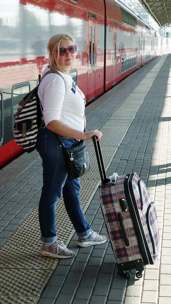 Woman traveler with Luggage arriving at the station waiting for the train. Travel concept for women.