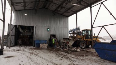 Atık işleme tesisinde işçi. Konveyör bant üzerinde çöp sıralama