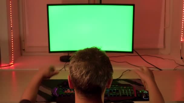 En man i hans hem kontor, framför en grön dataskärm. Arbeta hemma. — Stockvideo