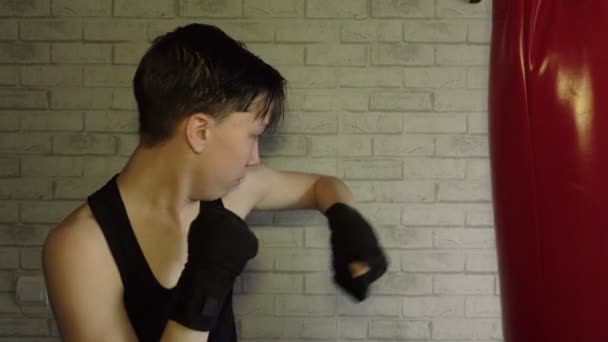 Een tiener in een zwart t-shirt in bokstraining. Slow Motion — Stockvideo