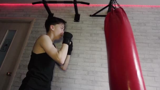 Een tiener in een zwart t-shirt in bokstraining. Slow Motion — Stockvideo