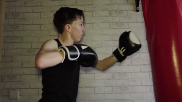 ボクシングのトレーニングで黒いTシャツを着たティーンエイジャー。スローモーション — ストック動画