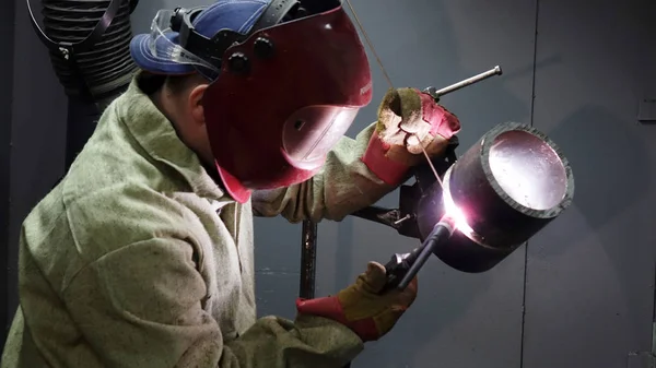 Welder in the mask. The metal product is welded by welding machine .