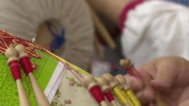 Dantel yakın çekim yapıyor. Bir kadın geleneksel şekilde dantel bobinler yapar.