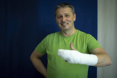 Kolu alçılı bir adam. Ameliyattan sonra sargı bezi verir..