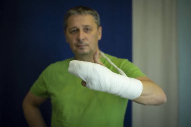 Kolu alçılı bir adam. Ameliyattan sonra sargı bezi verir..