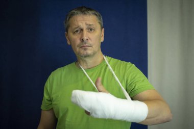 Kolu alçılı bir adam. Ameliyattan sonra sargı bezi verir..