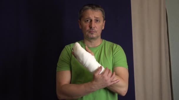 Un hombre se rasca el brazo con un yeso  . — Vídeo de stock