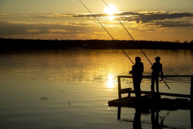 Gün batımında gölde iki balıkçı silueti .