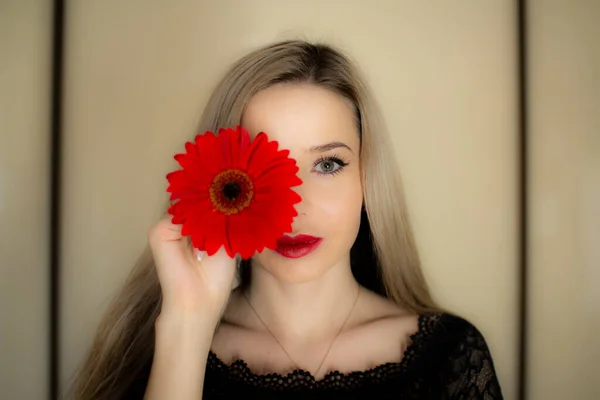Porträtt av en flicka med en röd Gerbera blomma. — Stockfoto