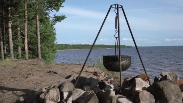 Uma panela no fogo junto ao lago. Acampar com uma panela sobre um fogo ardente. — Vídeo de Stock