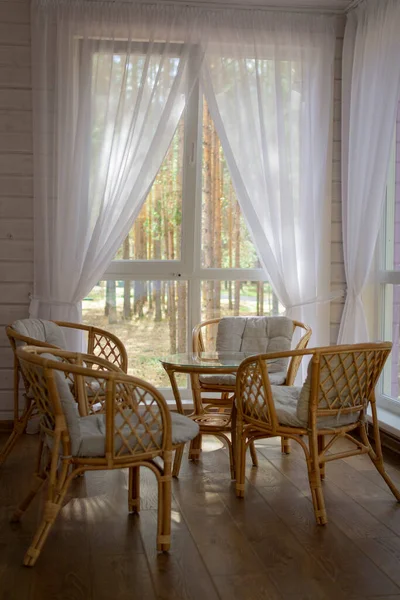Rattan furniture on the summer porch. Outside the window is a pine forest Stock Image
