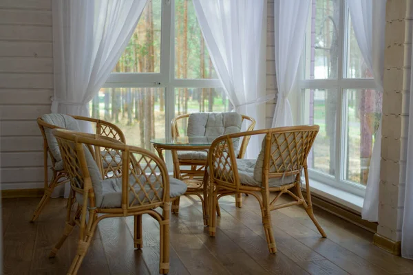 Rattan furniture on the summer porch. Outside the window is a pine forest Royalty Free Stock Photos