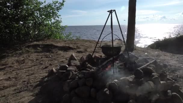Pot di atas api di tepi danau. Berkemah dengan panci di atas api yang membakar. — Stok Video