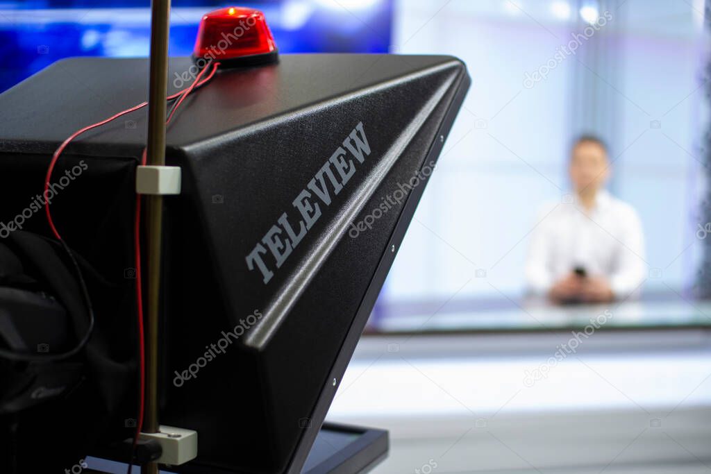 A male News anchor in a broadcast Studio reads text on a teleprompter. Camera in the TV Studio.