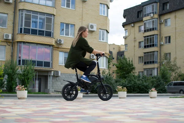 한 젊은 여자가 전기 자전거를 타고 도시를 누비고 다닌다. 로열티 프리 스톡 이미지