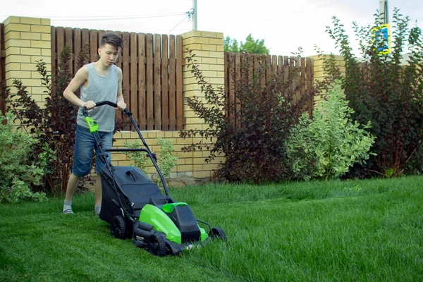 한 십 대는 잔디깎는 기계로 잔디를 깎는다. — 스톡 사진