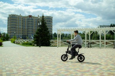 Bir genç şehirde elektrikli bisikletle geziyor..