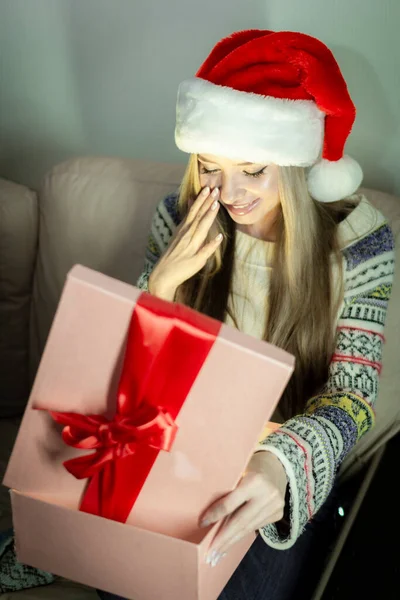 Красивая блондинка в новогоднем образе с подарочной коробкой в руках. Стоковое Фото