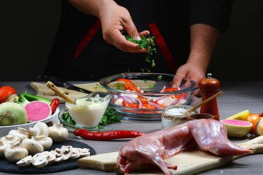 Karanlık bir arka plan üzerinde sebze ile profesyonel şef tavşan eti yemek pişirdim. hizmet fotoğraf arka plan. Yatay görünüm. seçici odak