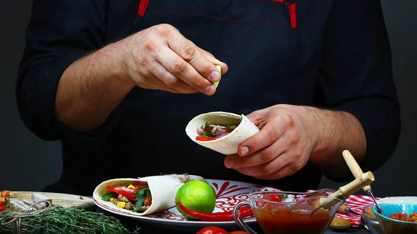 Lime splash in chef hand under mexican burito. Close up of a chef hands preparing mexican burito. The concept of mexican cooking recipe