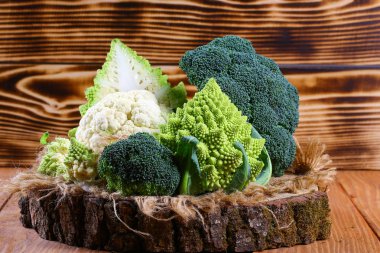 Many sorts of cabbage Broccoli, Romanesco on stump, rustic wooden background. clipart