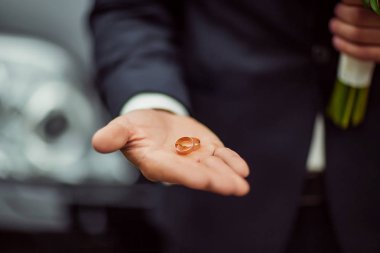 Altın alyanslar gelinin elinde bir buket çiçekli takım elbiseyle.