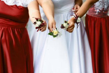 Gelin ve kız arkadaşlarının ellerinde kırmızı ve beyaz çiçeklerle güzel bir düğün yaka çiçeği..