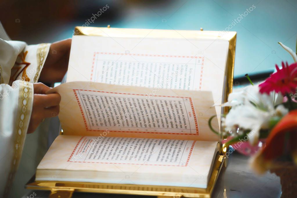 The Book of the Gospel is open for reading in the hands of the priest at the wedding.