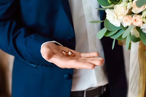 新郎は金の結婚指輪を手に持っています 結婚式で花束を持つ新郎 結婚式と様式の概念 — ストック写真