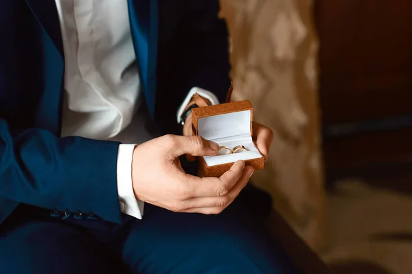The groom is holding a box with wedding rings before the wedding ceremony. Men's hands holding a box with rings.